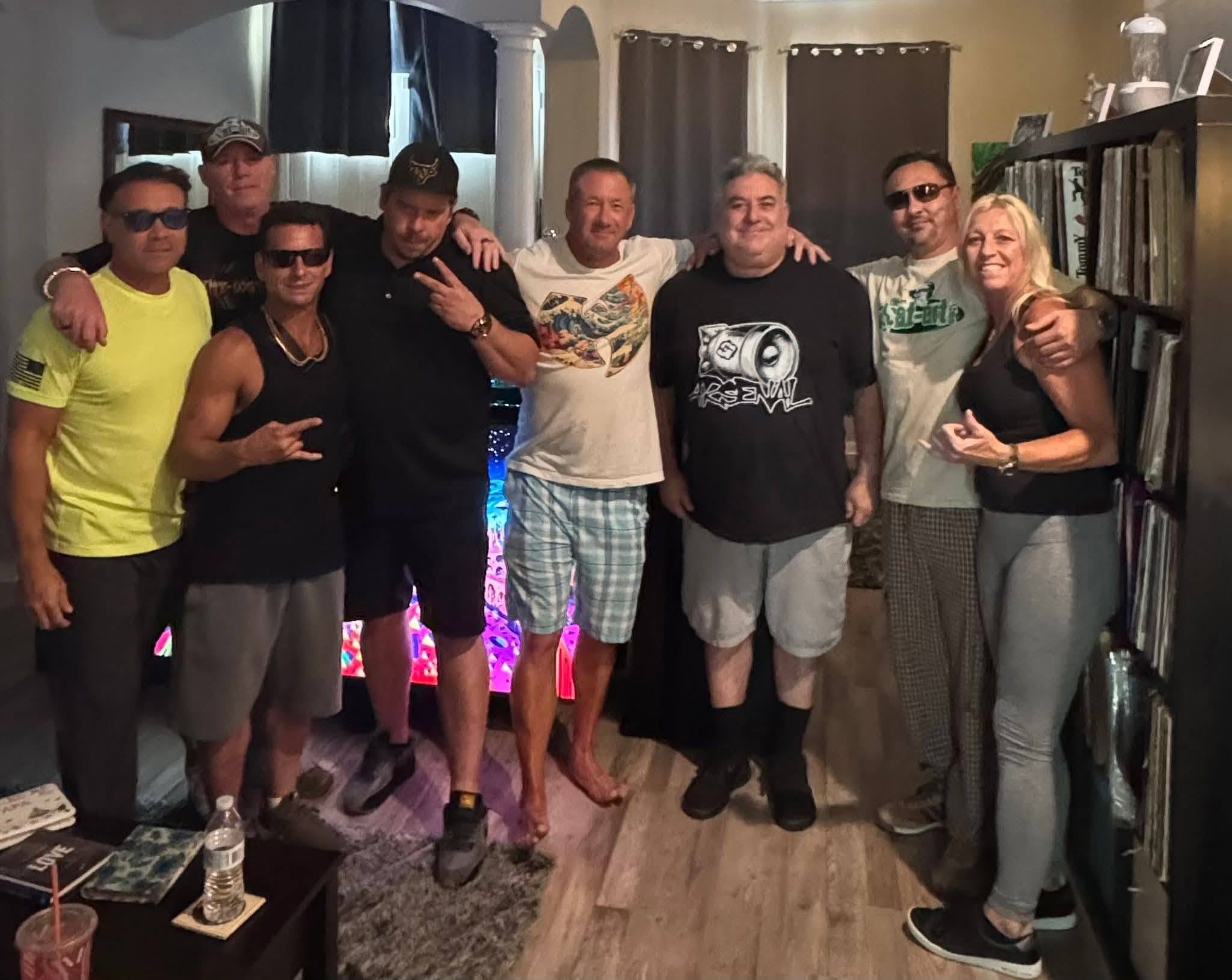 Eight people including DJ Natural Nate® gathered in a vinyl record room with neon lighting at the Florida underground show May 2026
