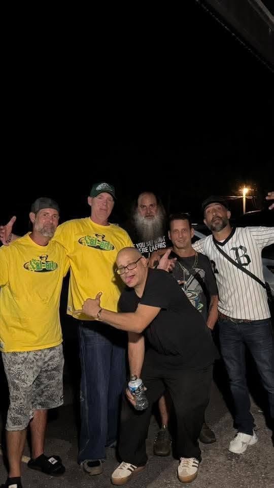 Five people including DJ Natural Nate® in The-Lost-Art.com yellow shirts outside at night at the Florida underground show May 2026