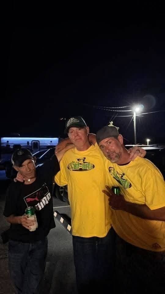 Three people including DJ Natural Nate® in The-Lost-Art.com yellow shirts outside at night at the Florida show May 2026